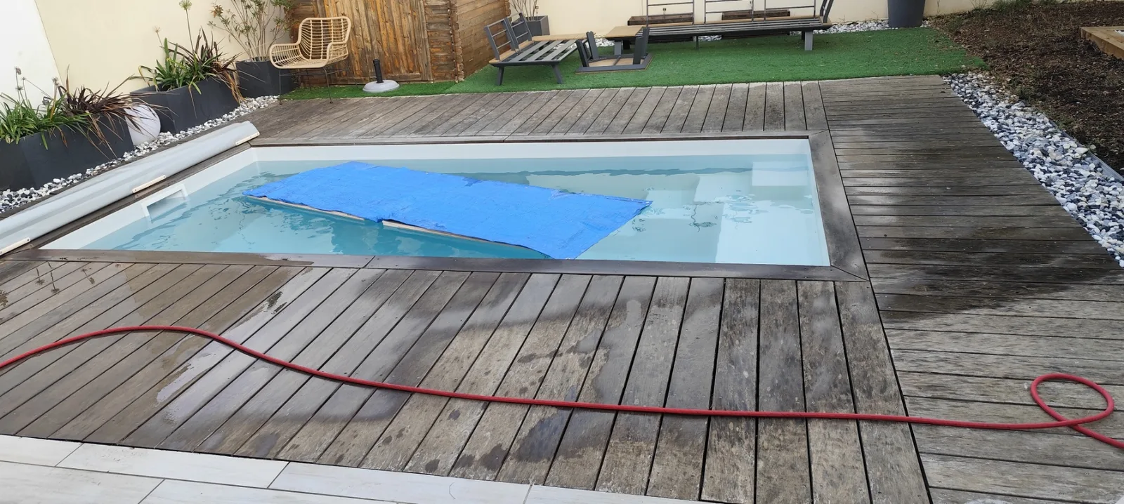 Terrasse en bois autour d'une piscine en cours de nettoyage