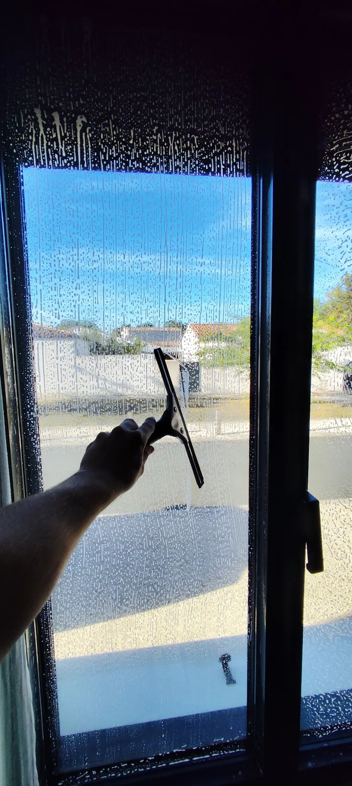 Lavage d'une vitre à la raclette